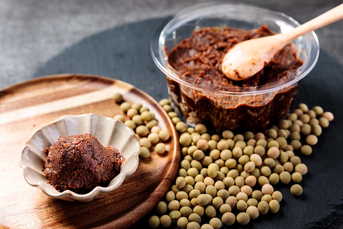 容器と食器に入っ味噌とスプーン、大豆が映った写真
